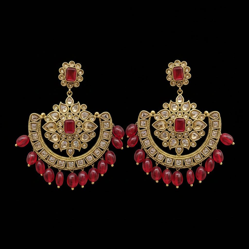 A pair of ornate gold-toned traditional Indian earrings with red stones and dangling red bead chains, displayed on a gray stand against a light gray background. The brand name 'SAHELI MY BEST FRIEND' is visible at the top.
