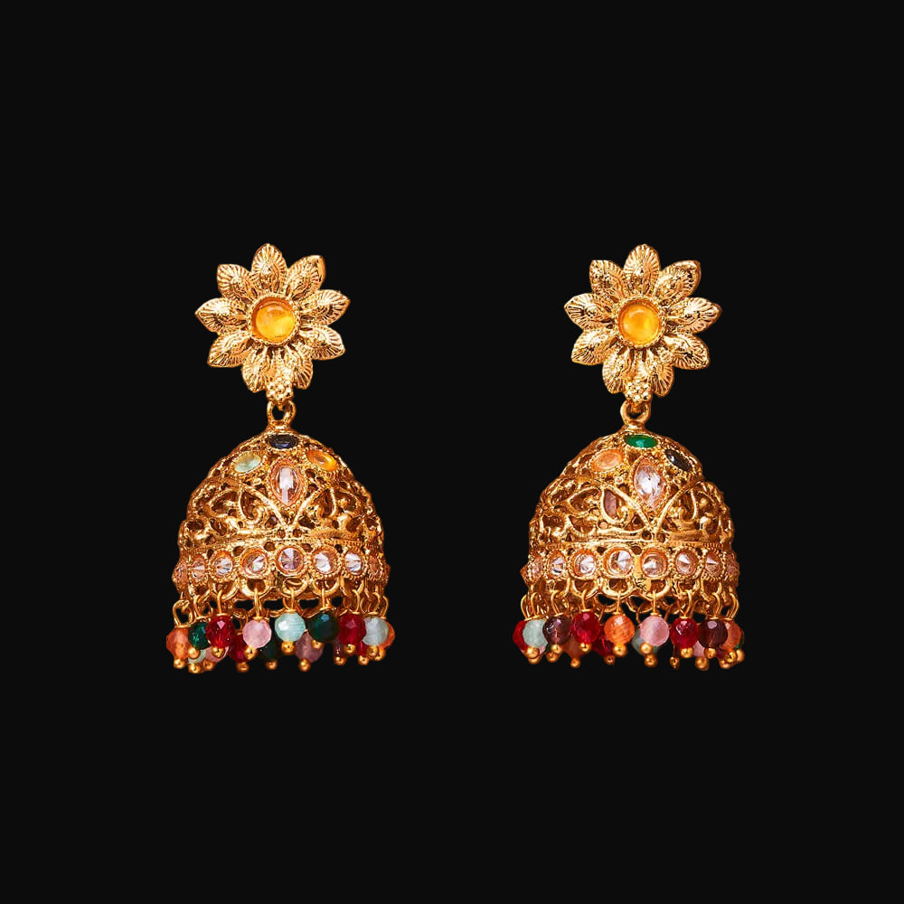 Gold earrings with floral top and colorful beads on a brown background