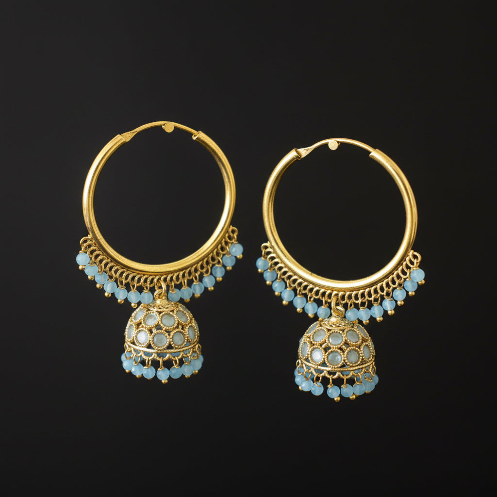 Gold hoop earrings with blue gemstones on a gray stand against a dark background