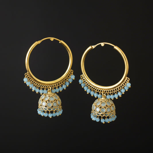 Gold hoop earrings with blue gemstones on a gray stand against a dark background