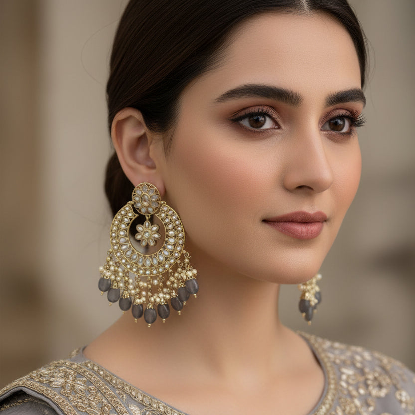 Ornate gold and black earrings with 'SAHELI' branding on a dark background