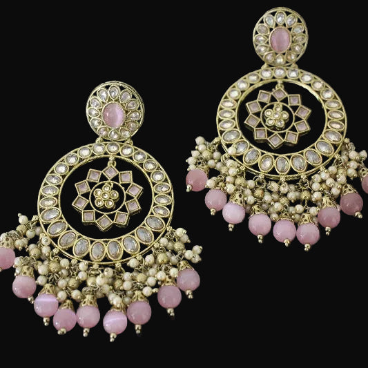 Ornate gold and pink earrings on a dark background with 'Saheli' branding.