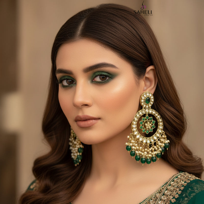 Ornate gold and green earrings with 'Saheli' branding on a gray background