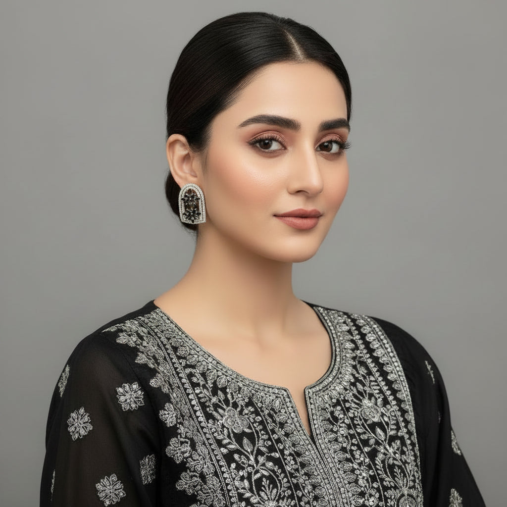 Pair of silver earrings with gemstones on a gray background, featuring the Saheli brand.