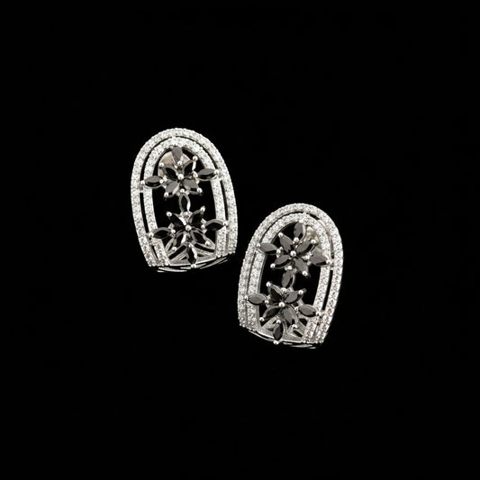 Pair of silver earrings with gemstones on a gray background, featuring the Saheli brand.