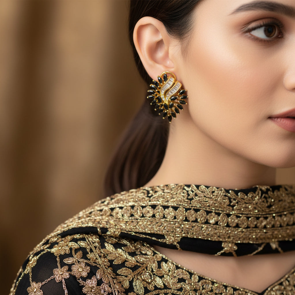Gold and black earrings on a gray background with 'SAHELI' brand logo.