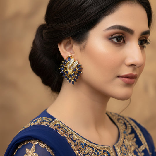 Pair of gold and blue earrings on a dark background with 'SAHELI' branding.