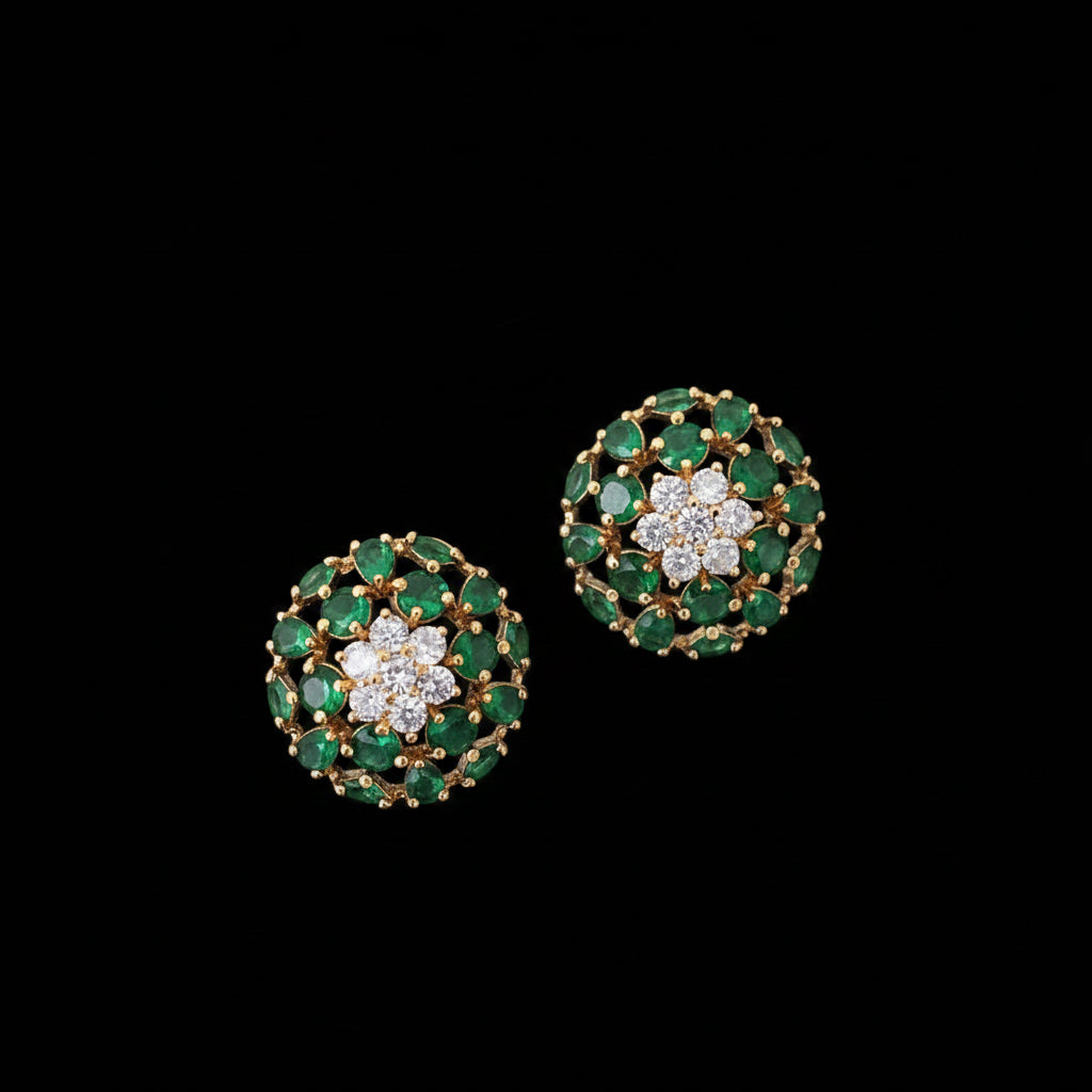 Pair of emerald and diamond earrings on a dark background with 'Saheli' branding.