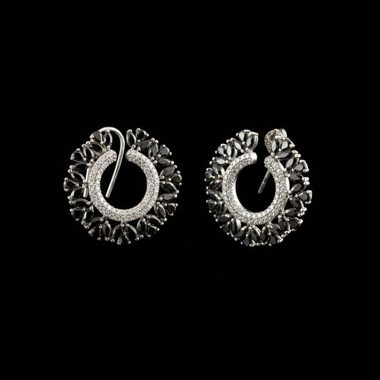 A pair of silver crescent-shaped hoop earrings with intricate filigree detailing and clear stones, displayed on a dark reflective surface with the brand logo 'SAHELL MY BEST FRIEND' above them.