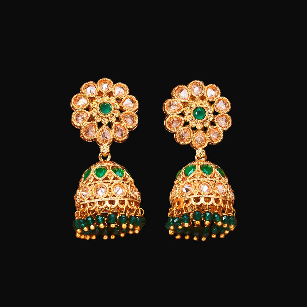 Gold and green floral earrings on a brown background