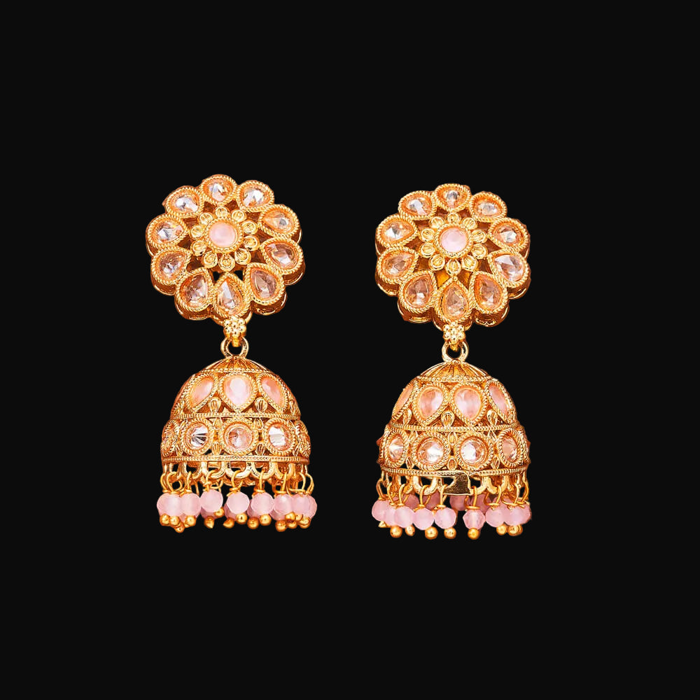 Gold and pink earrings on a brown background