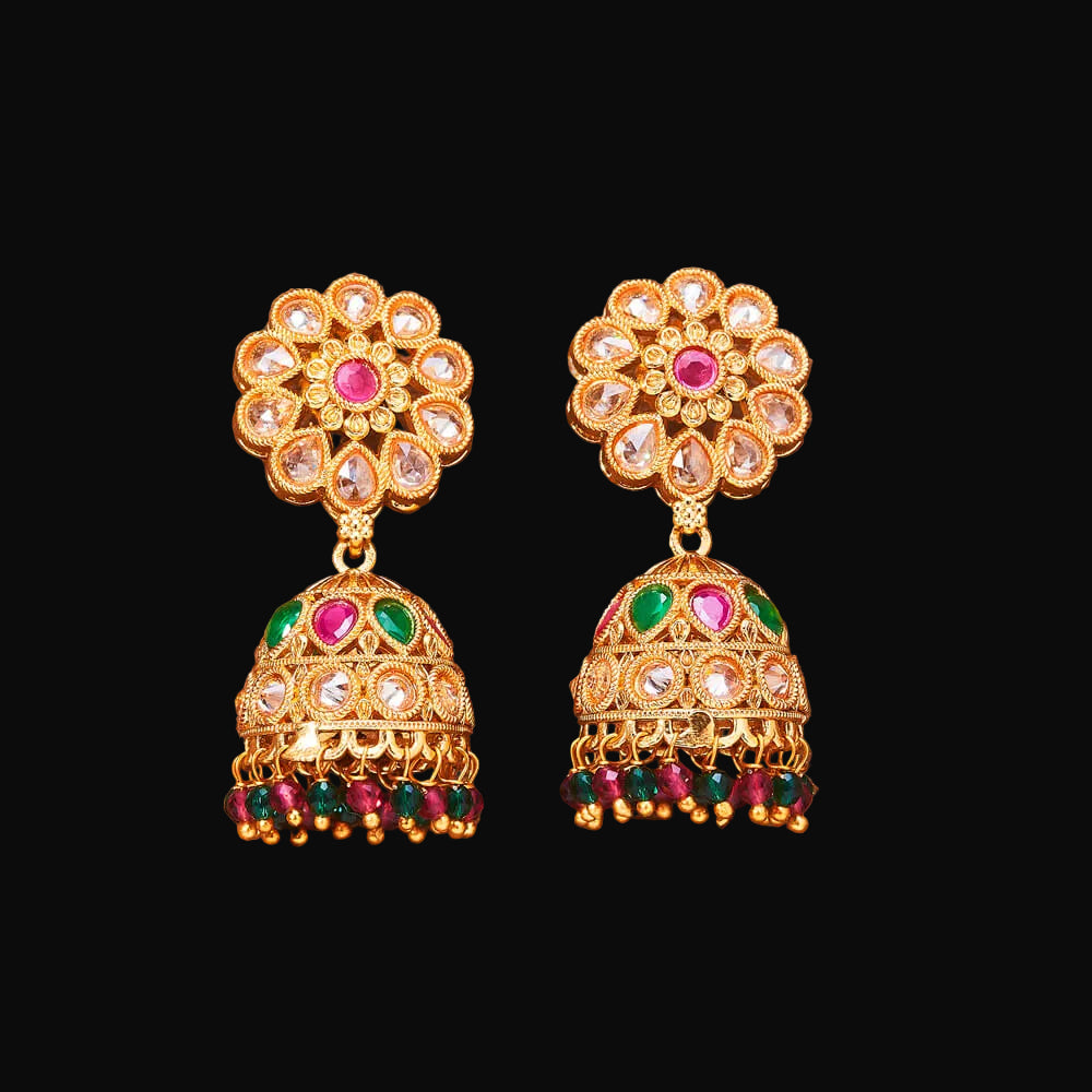 Gold earrings with colorful gemstones on a brown background