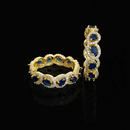 Gold and blue gemstone jewelry set with 'SAHELI' branding on a gray background