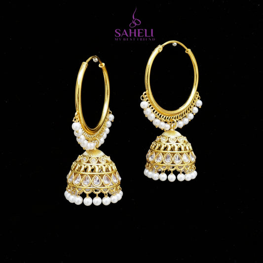 Gold hoop earrings with jhumka designs on a black background, featuring the brand 'Saheli'.