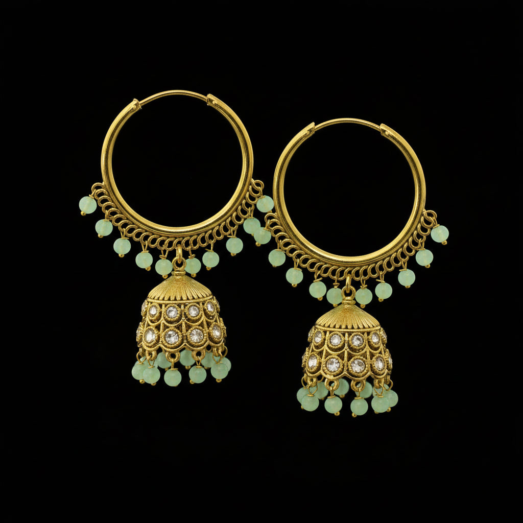 Gold hoop earrings with green gemstones on a black stand