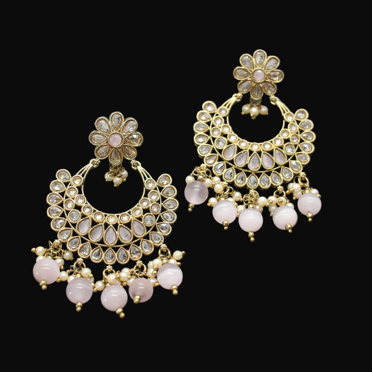 Pair of gold and pink earrings on a dark gray background