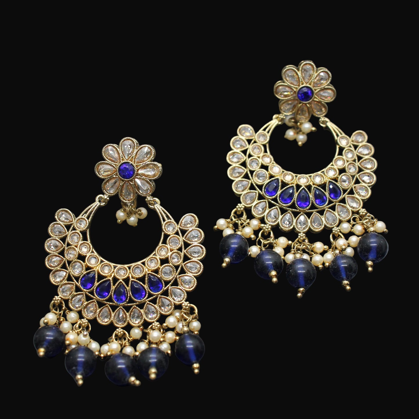 Pair of ornate earrings with blue stones on a dark background