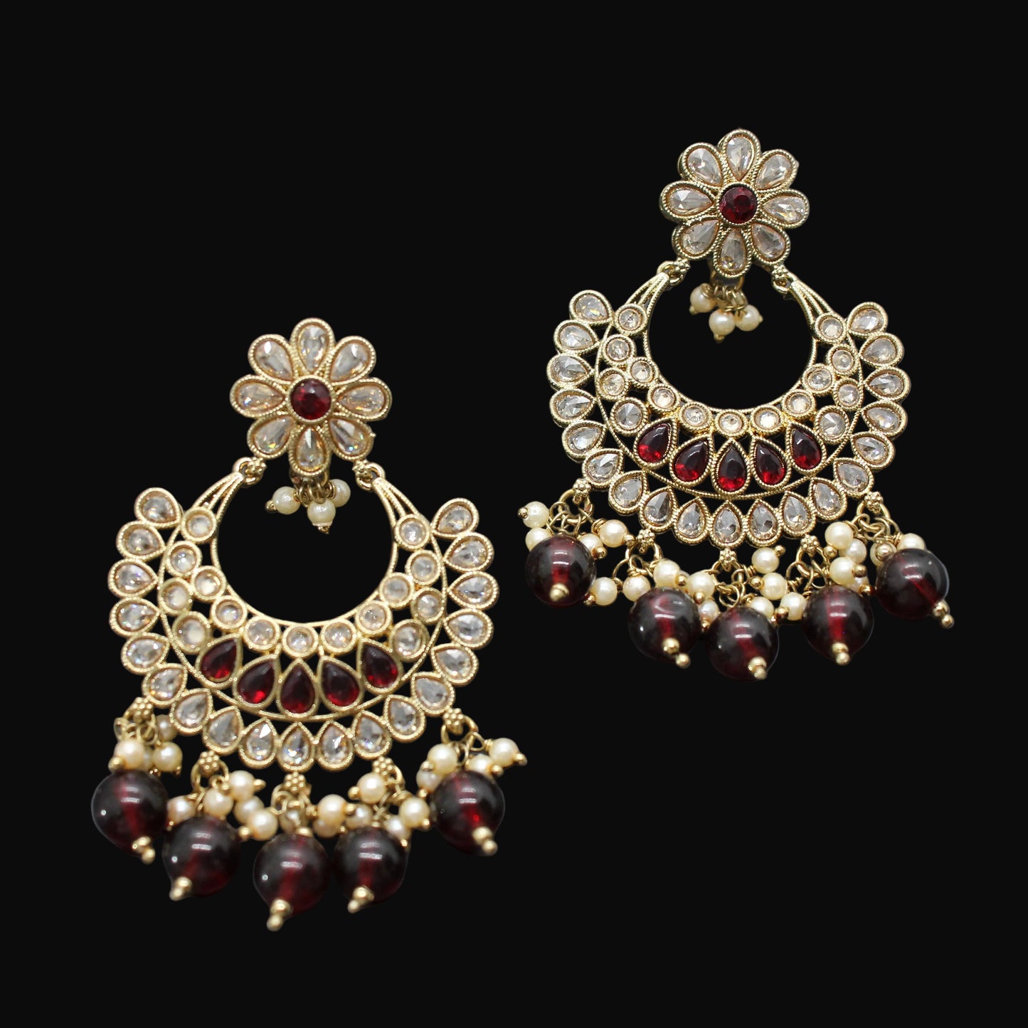 Pair of gold and red gemstone earrings on a dark background