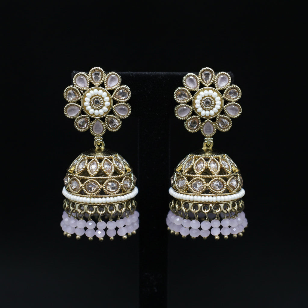 Pair of gold and crystal jhumka earrings on a black background