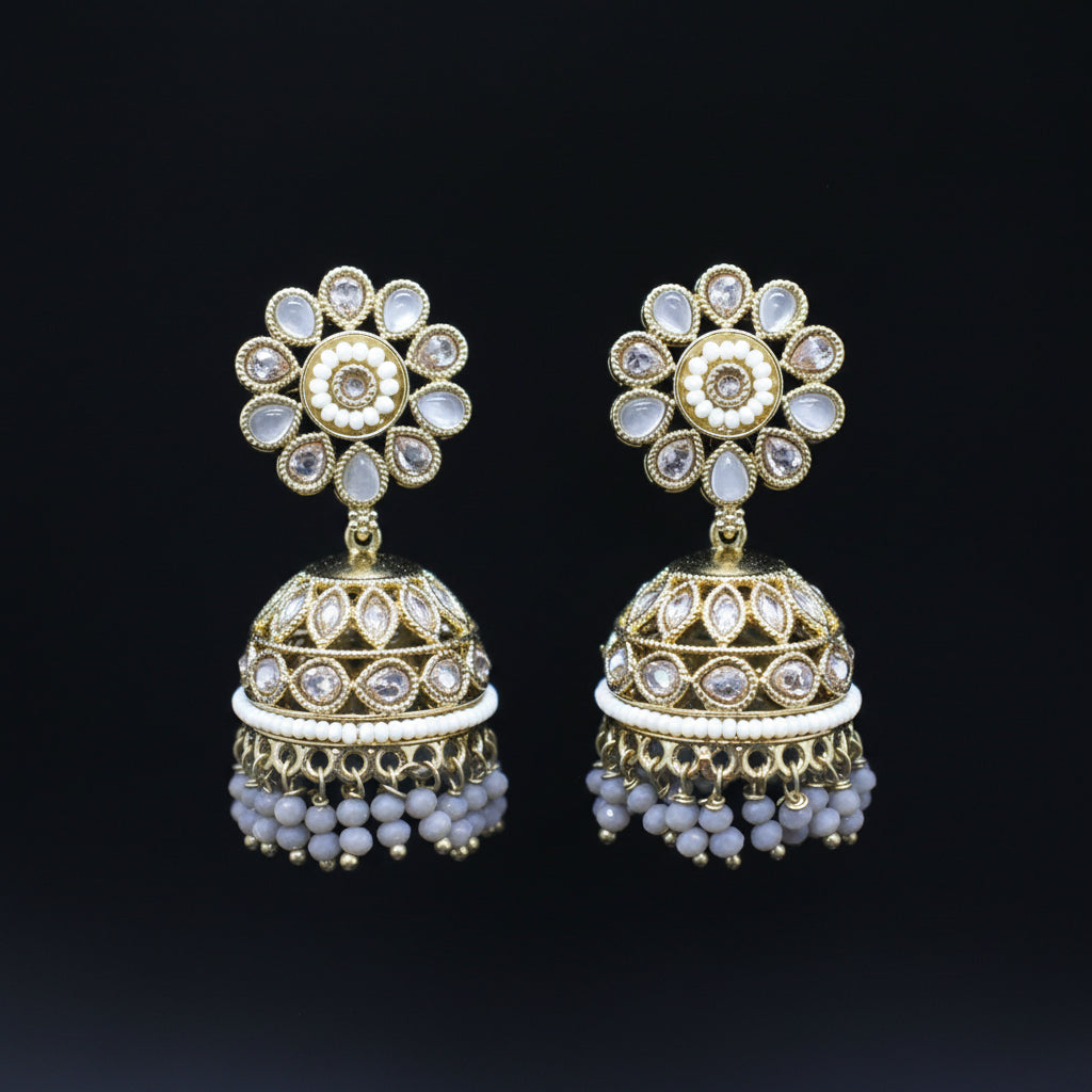 Pair of gold and pearl earrings on a black stand with a dark background