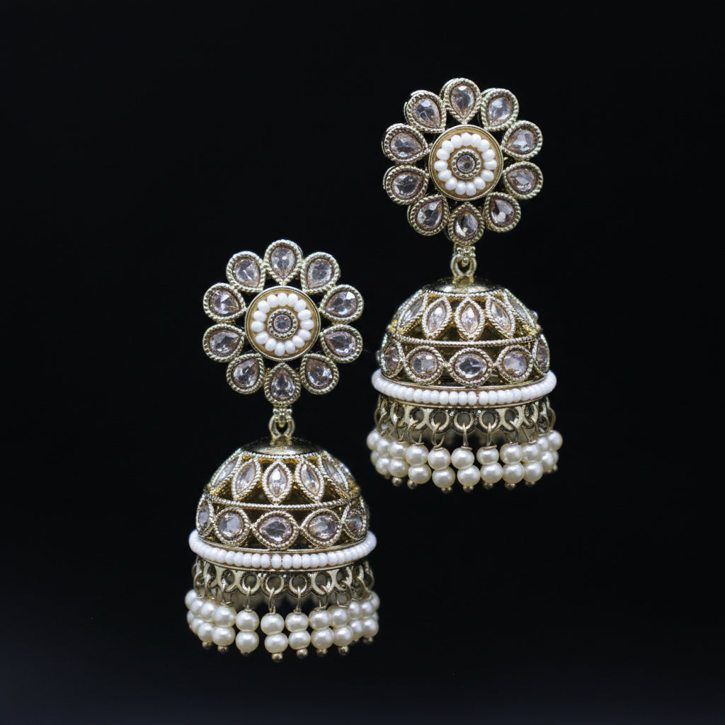 Pair of ornate earrings with floral top and bell-shaped bottom on a dark background