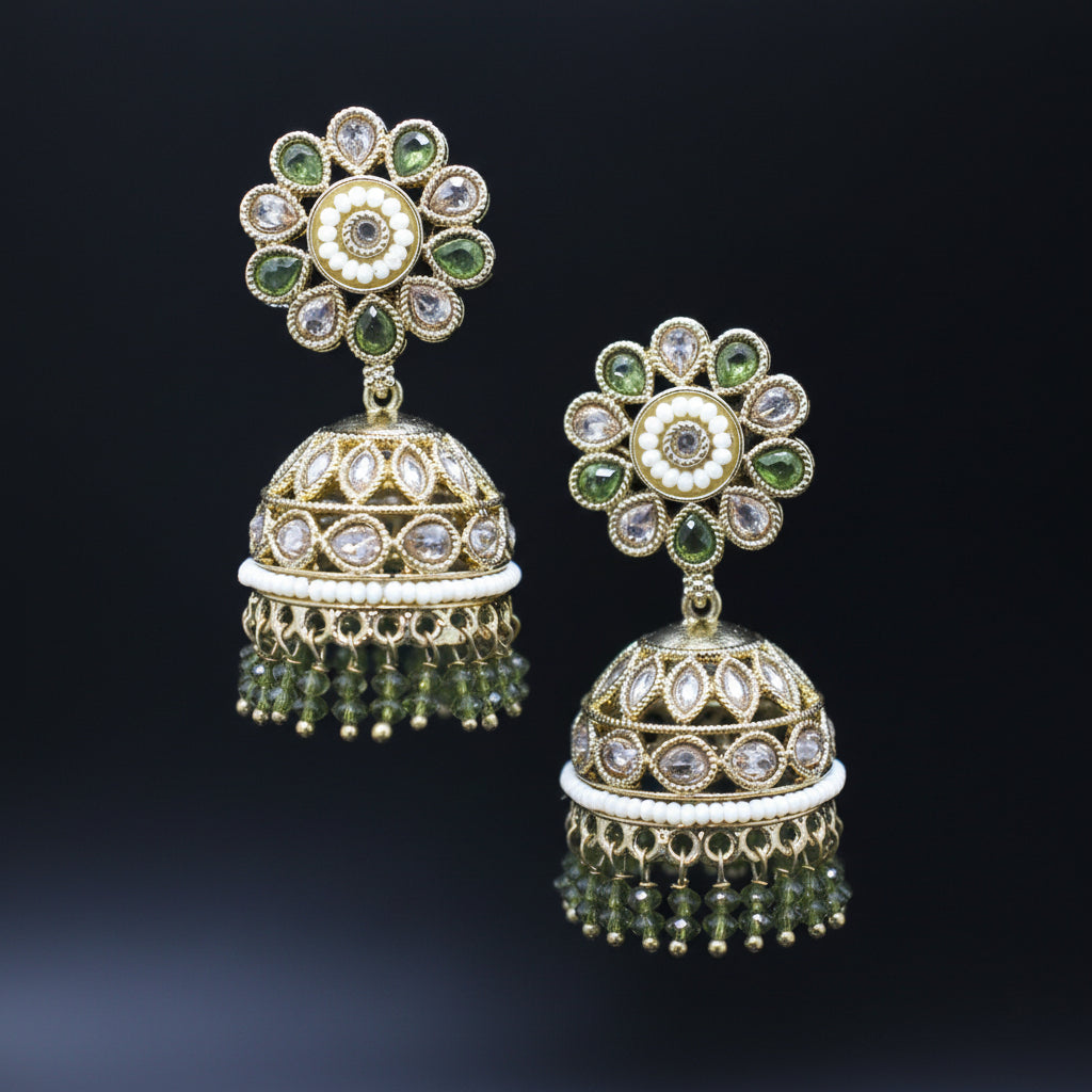 Pair of ornate earrings with green and clear gemstones on a black background