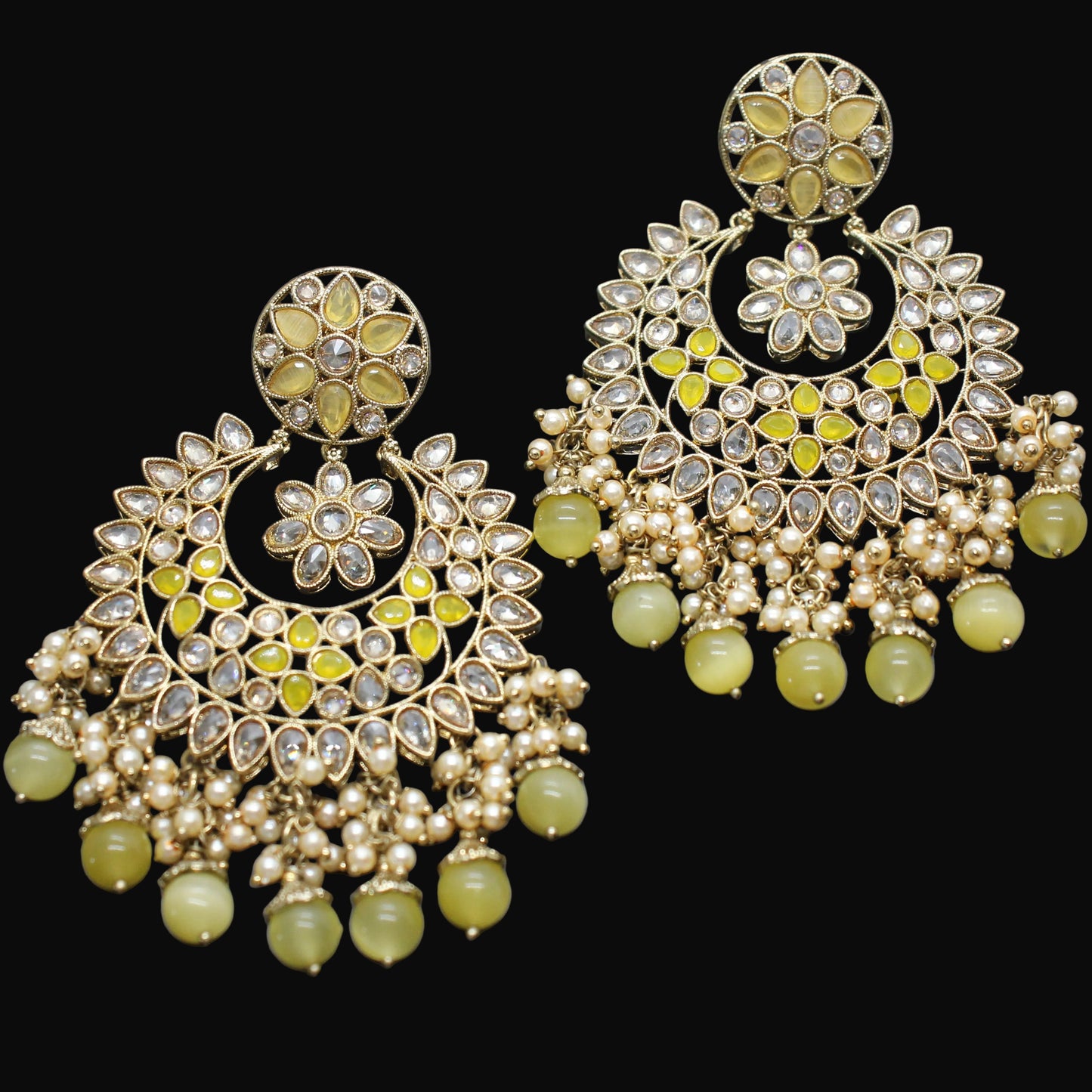 Ornate earrings with green beads on a dark gray background