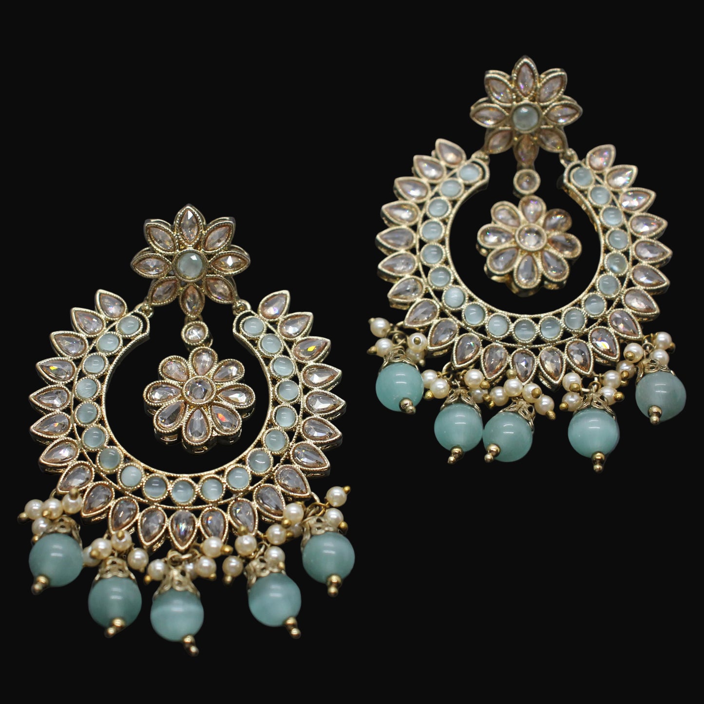 Ornate earrings with floral designs and turquoise beads on a dark background