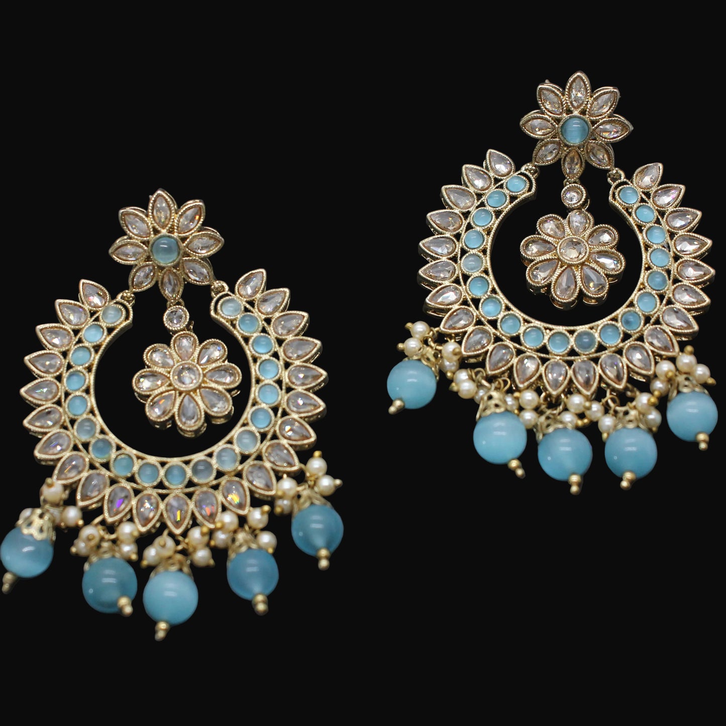 Pair of ornate earrings with turquoise beads on a dark background