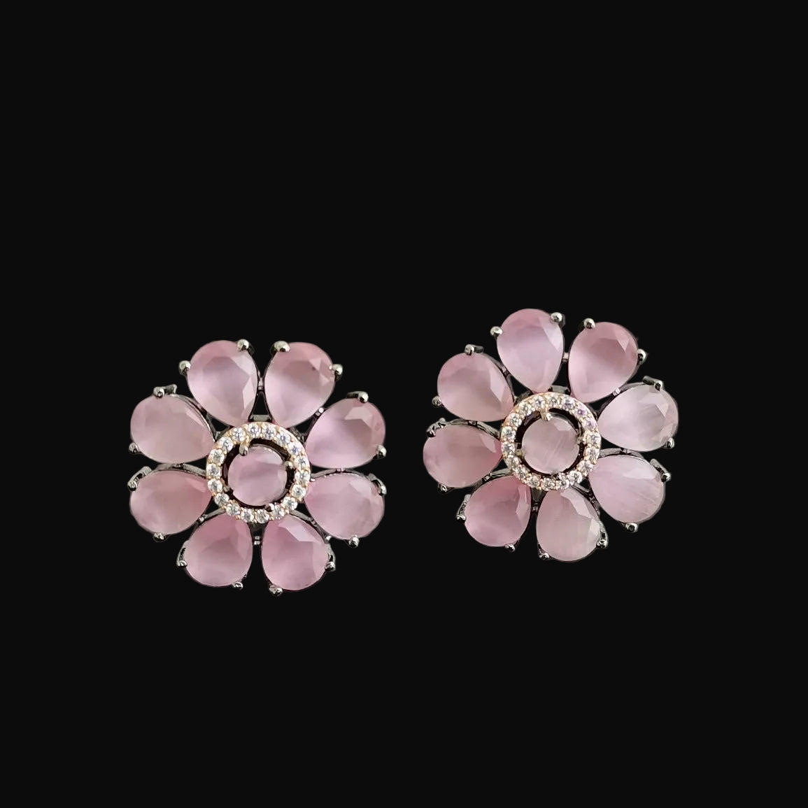 Pair of pink flower-shaped earrings on a dark gray background