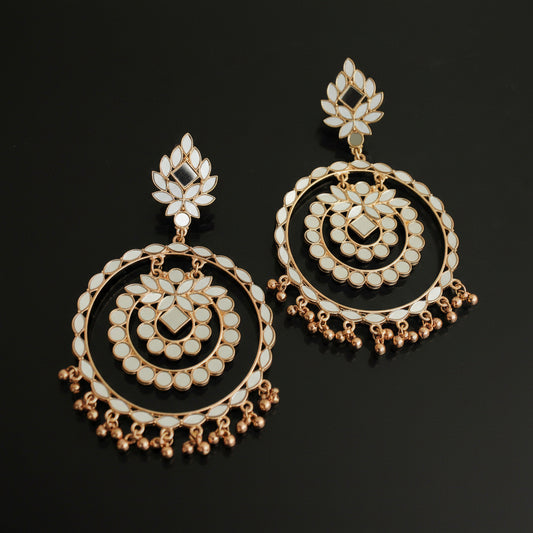 Pair of gold and pearl earrings on a dark background with 'Saheli' branding.