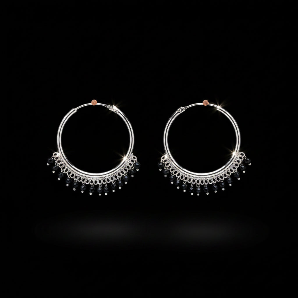 A pair of silver hoop earrings with dangling beaded fringe, displayed on a textured orange-brown background.