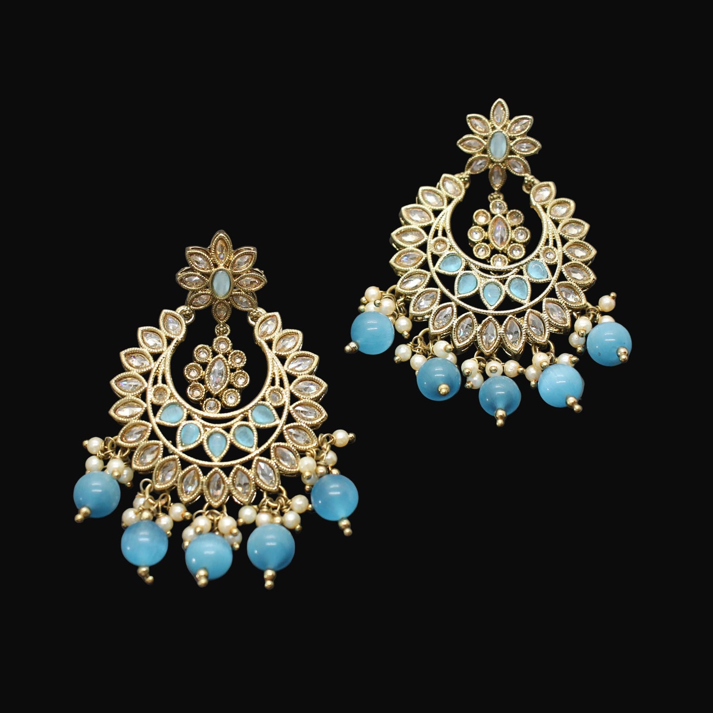Pair of gold and turquoise earrings on a dark gray background