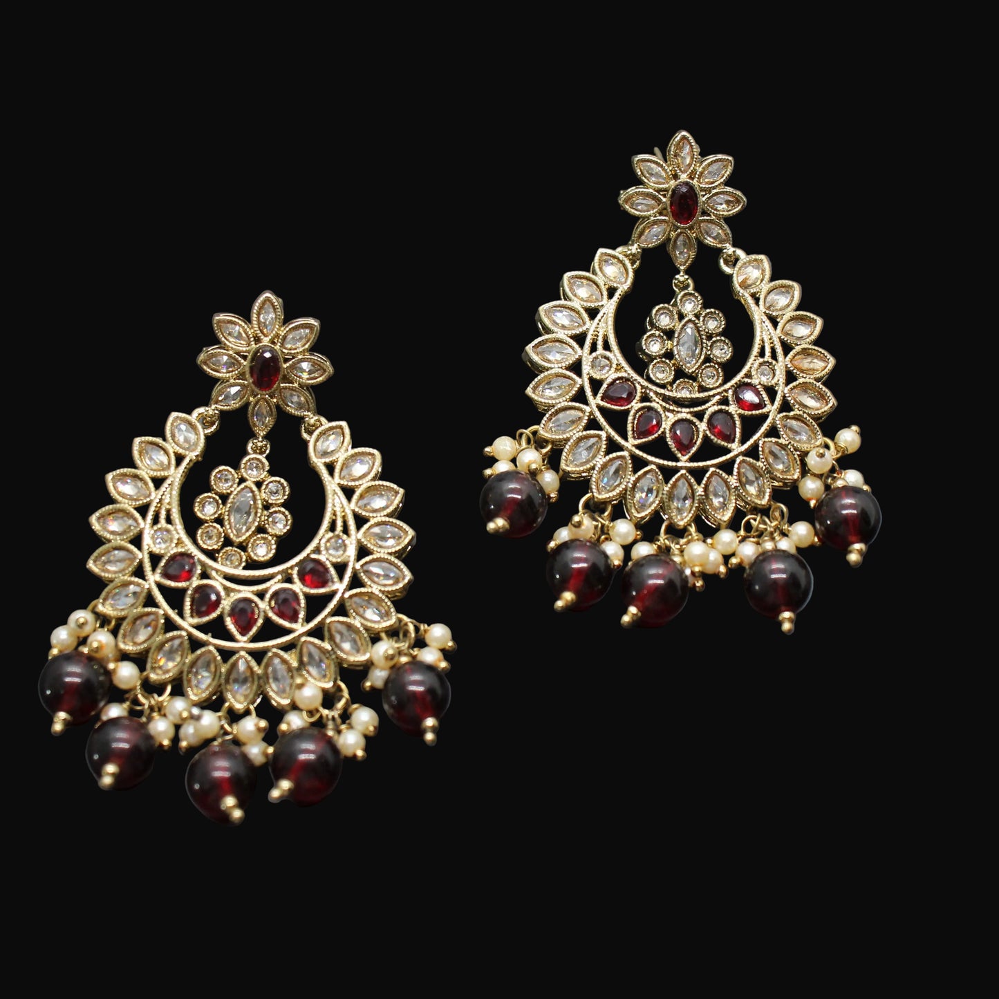 Pair of gold and red beaded earrings on a dark gray background