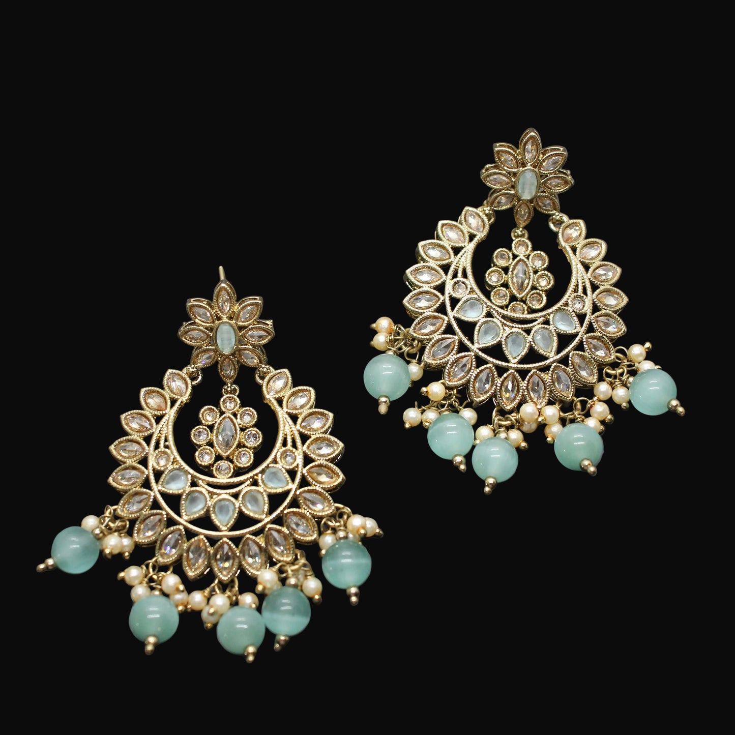 Pair of gold and turquoise earrings on a dark gray background