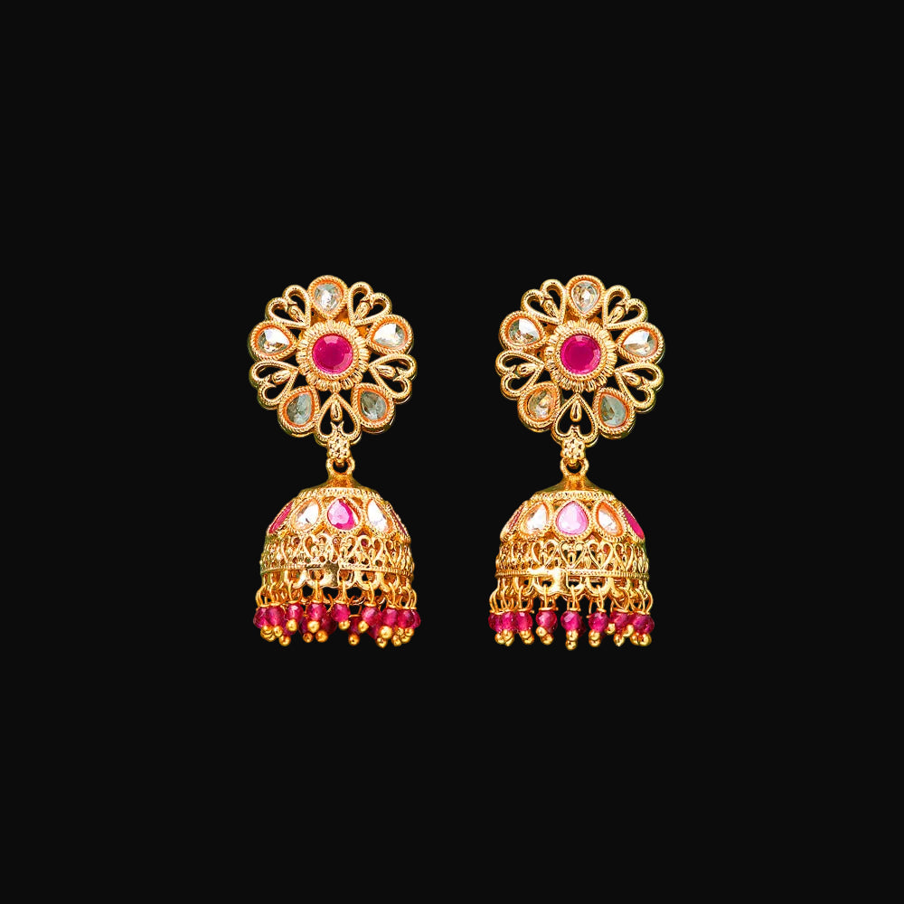 Gold and pink earrings on a teal background