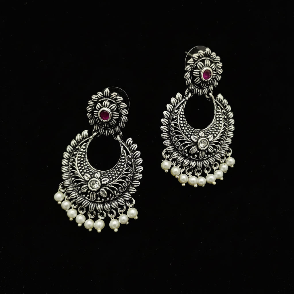Pair of silver earrings with pearls and gemstones on a black background