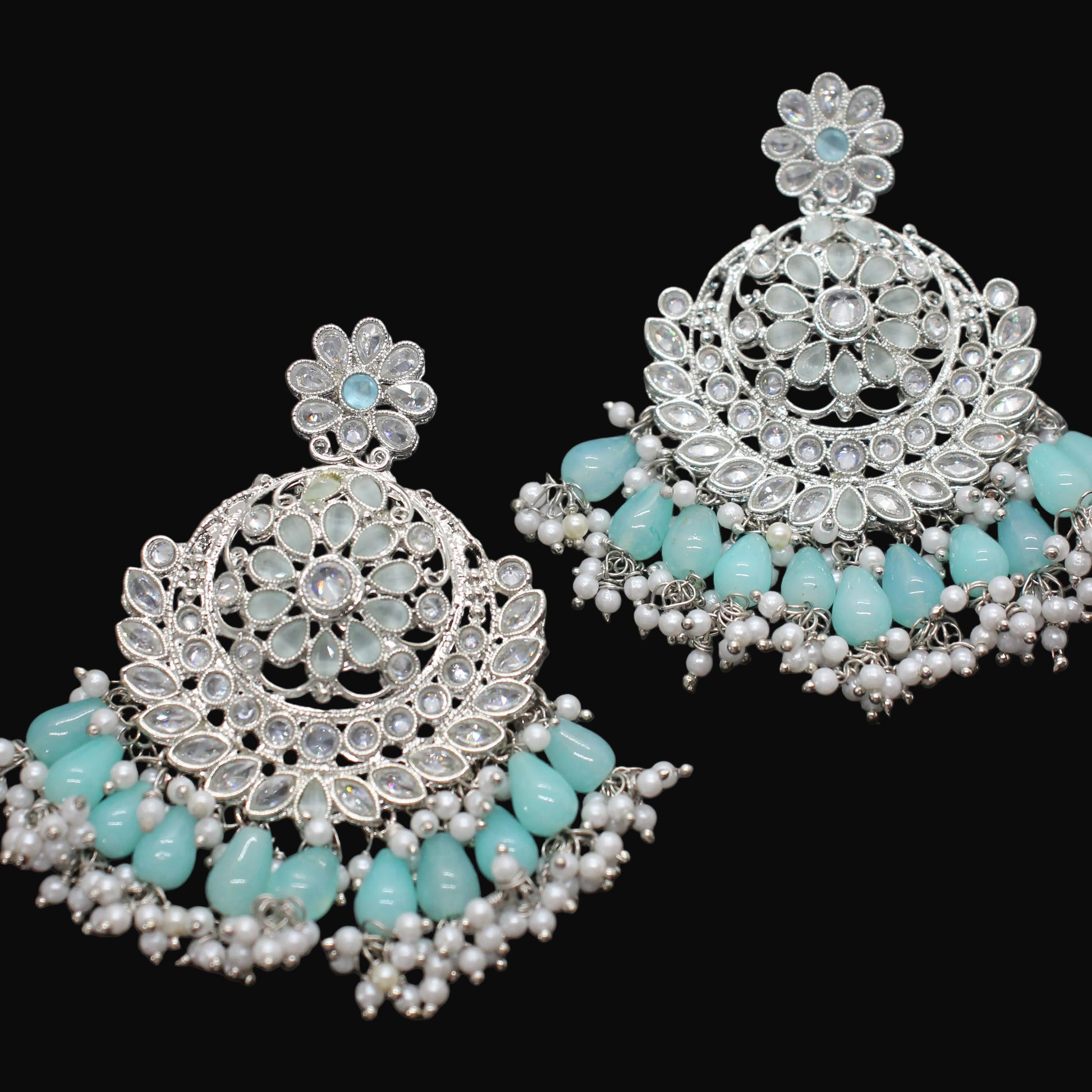 Pair of silver earrings with turquoise stones on a gray background