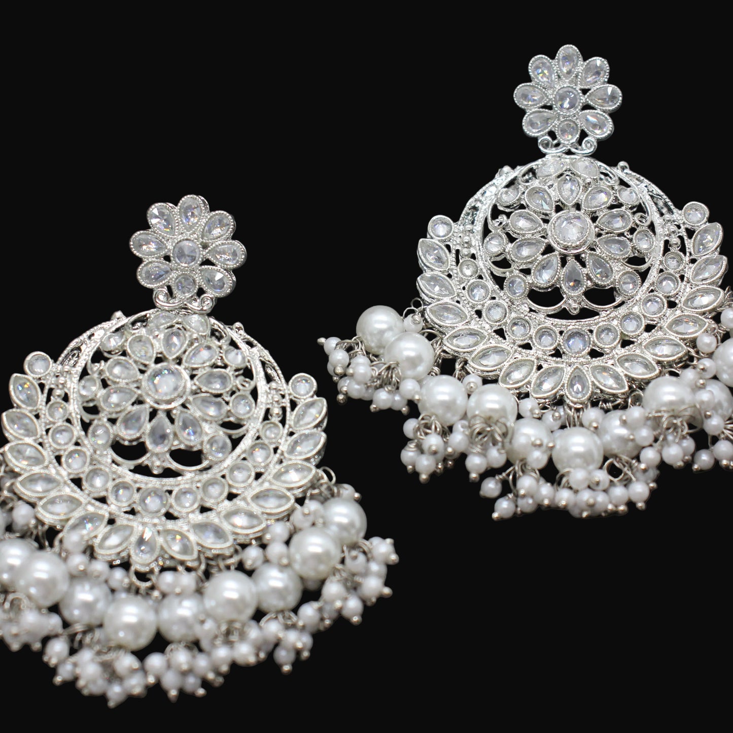 Pair of silver and pearl earrings on a dark background