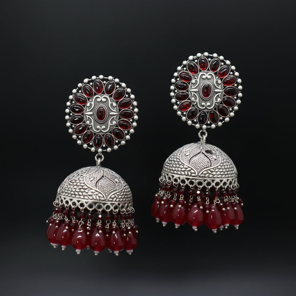 Pair of silver and red earrings on a dark background