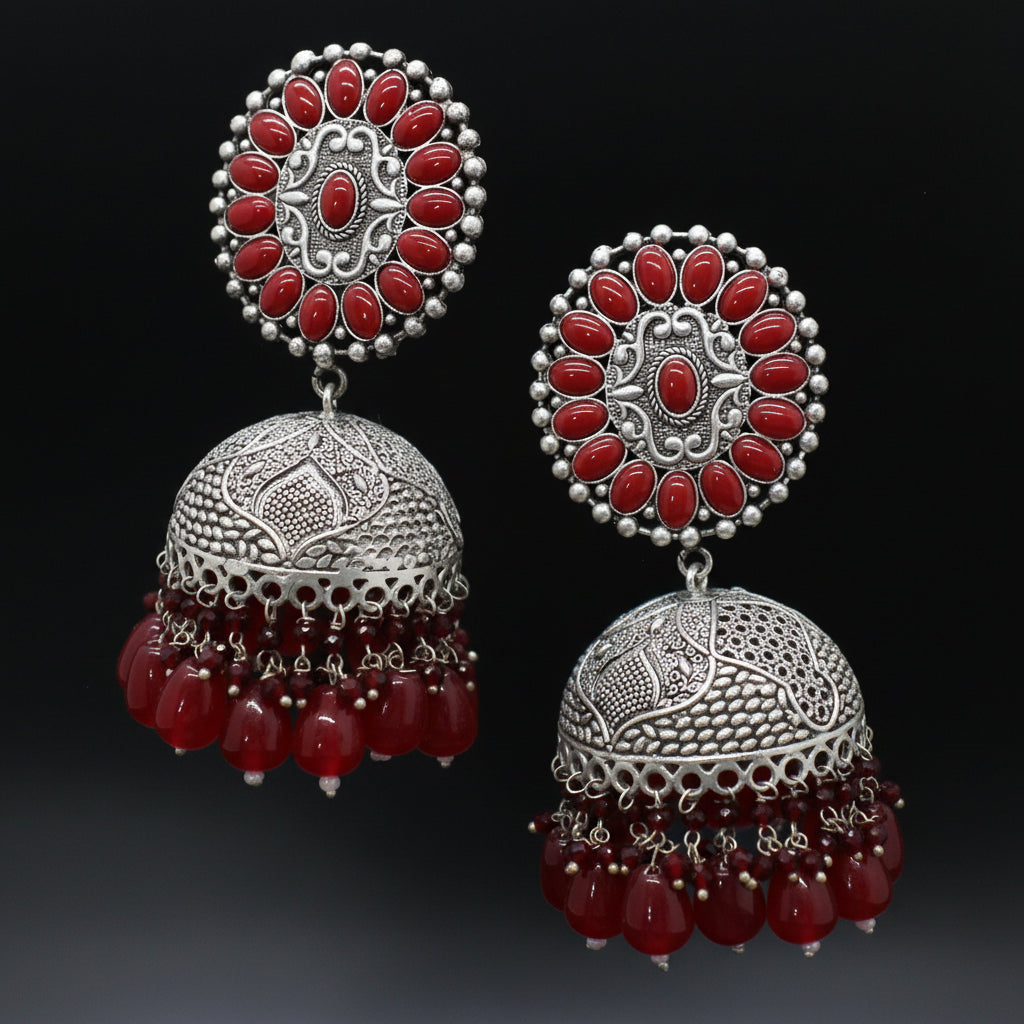 Pair of silver and red earrings on a black background