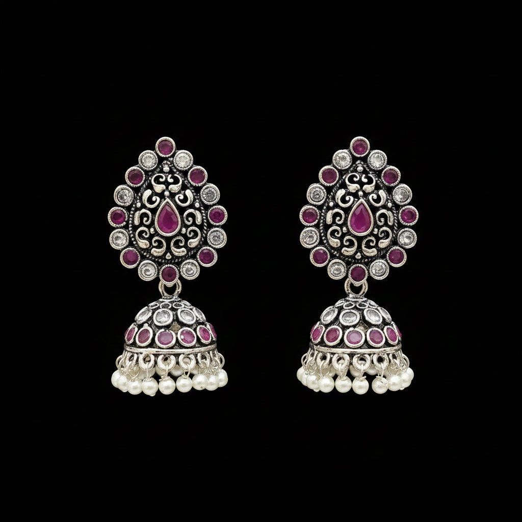 Pair of silver and pink earrings on a gray stand with 'Saheli' branding.