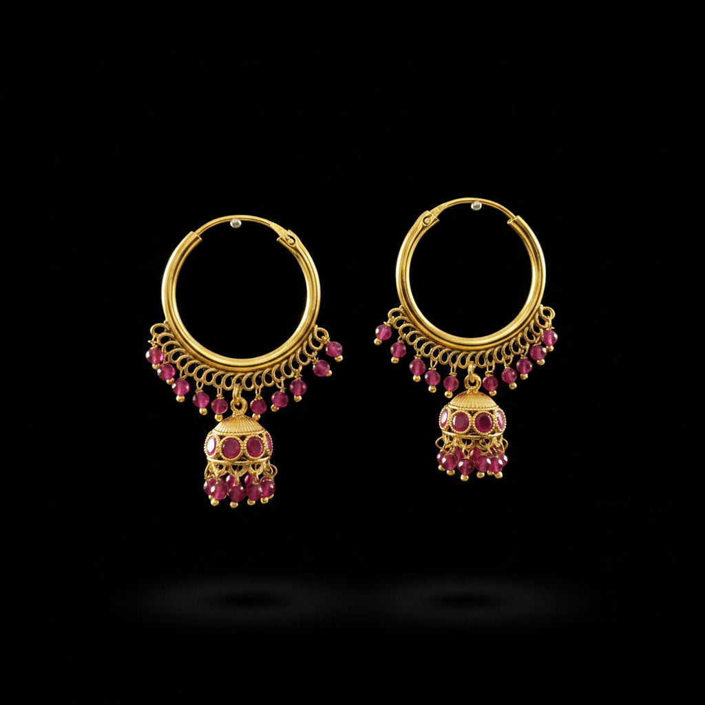 A pair of gold-toned huggie hoop earrings with dangling chains, pink gemstone accents, and bell-shaped jhumka drops, displayed on a gray jewelry stand. The brand logo 'SAHELL MYBESTFRIEND' is visible at the top center.