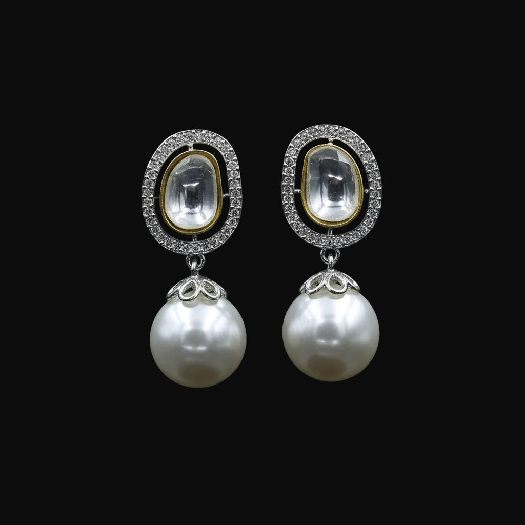A pair of gold and silver drop earrings with oval clear stone tops and large white pearl drops, displayed on a black stand against a black background with the SAHELL MY BEST FRIEND logo above.