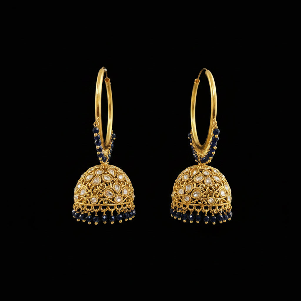 A pair of gold-plated Indian jhumka earrings with navy blue bead accents and clear stone embellishments, displayed on a black stand against a gray background. The brand logo 'SAHELI MY BEST FRIEND' is visible in the top left corner.
