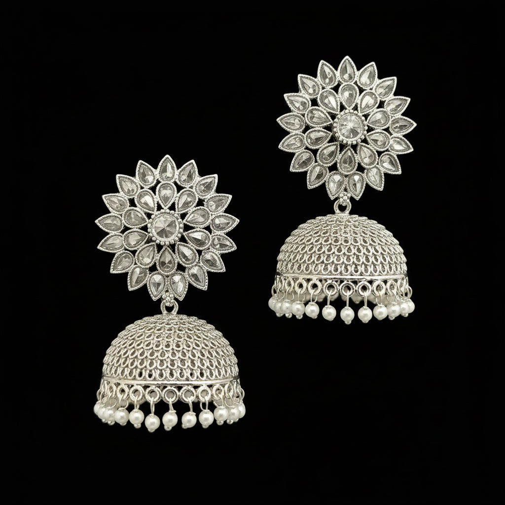 Silver floral earrings with pearl details on a gray stand.