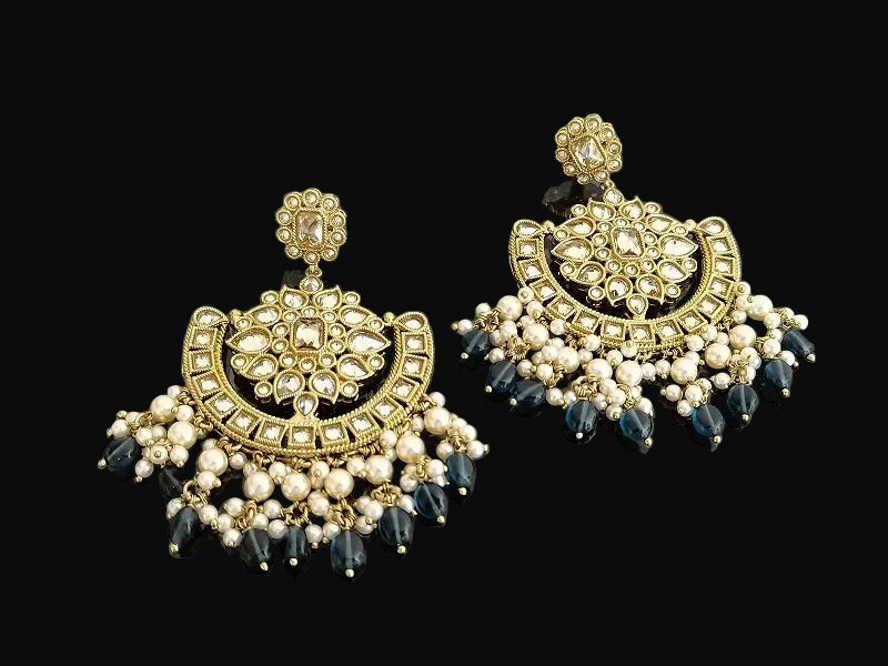 Pair of ornate earrings with gold, black, and pearl details on a dark background
