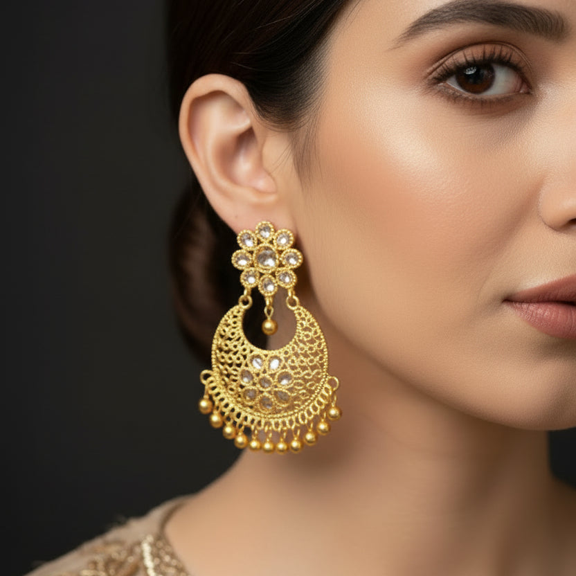 Gold earrings with intricate designs on a black background, featuring the brand 'Saheli'.