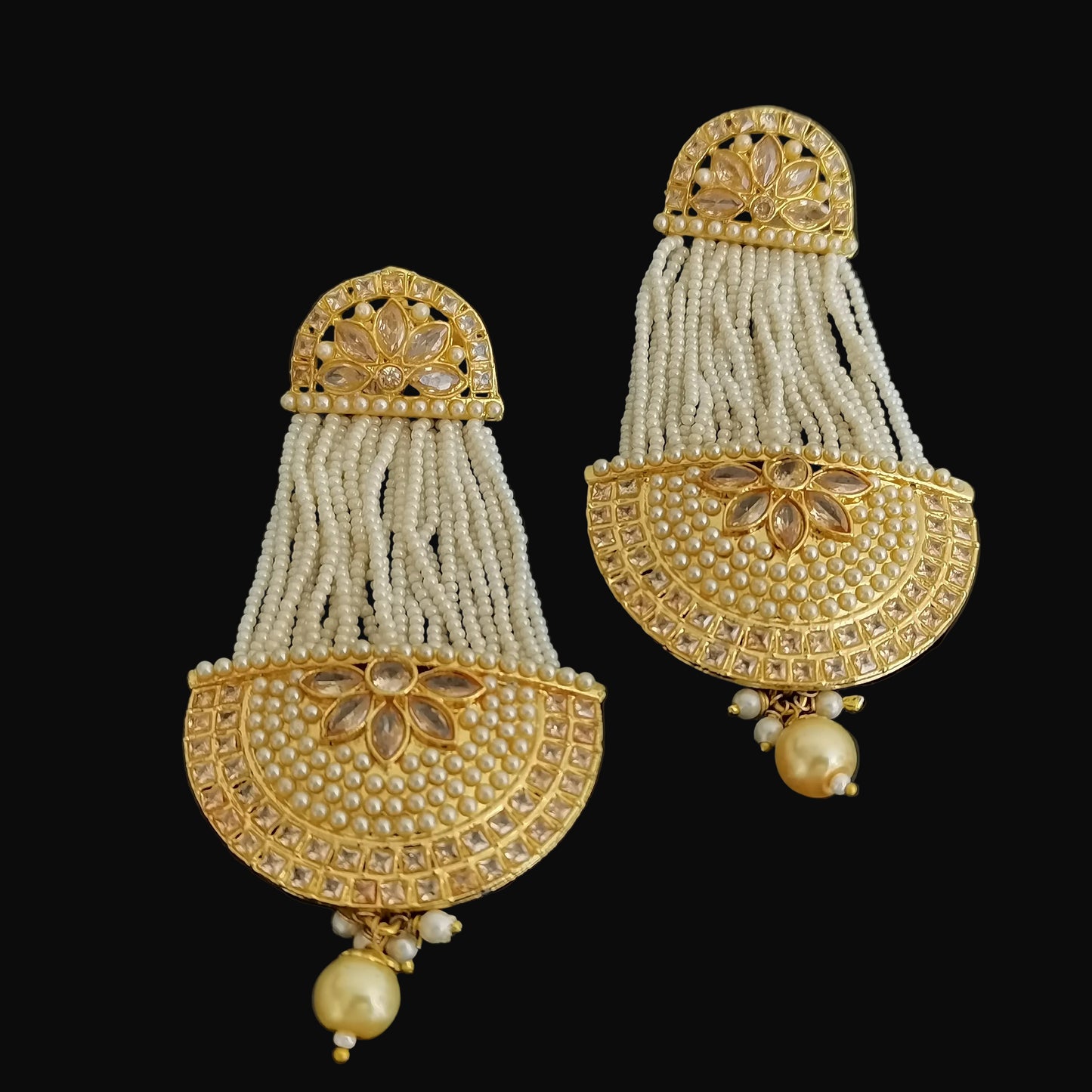 Pair of gold and pearl earrings on a dark background