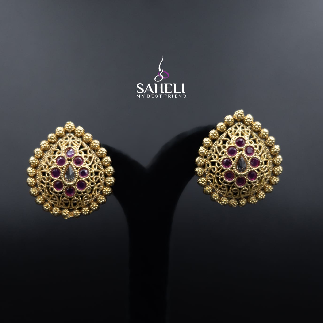 Gold earrings with purple stones on a dark background, featuring the Saheli brand.